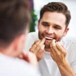 A man is brushing his teeth in front of a mirror.