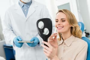 woman looking herself in the mirror after dental implant